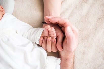 赤ちゃんの手を家族で包む